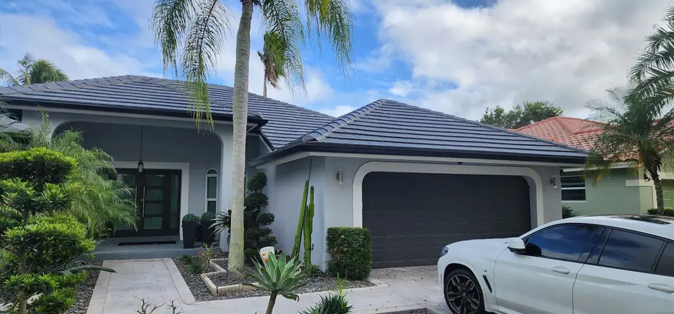 A grey home with a dark tile roof and a white gutter