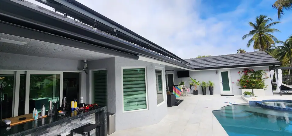 A long dark gutter on a grey home beside a pool