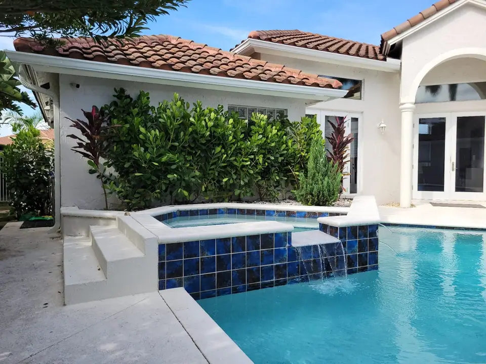 White gutters on a tile-roof home above a pool and spa