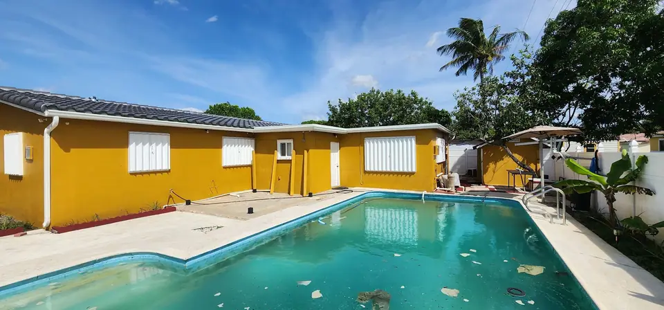 Gutters on a yellow stucco home above a backyard pool